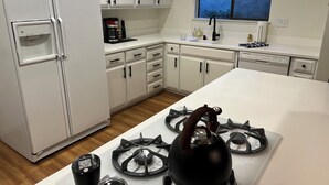 Una cocina moderna con armarios blancos, una estufa a gas, un refrigerador y una ventana con vistas.
