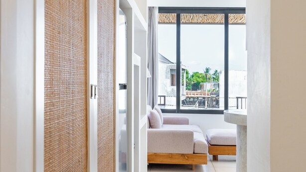 Una habitación de hotel moderna con un ventanal grande, un sofá y suelo de madera.