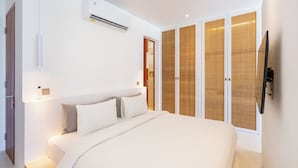 Un dormitorio moderno con una cama grande, aire acondicionado, un armario y un televisor.