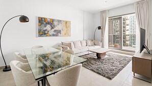Een moderne woonkamer met een glazen eettafel, een beige bank en een groot abstract schilderij.