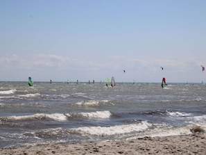 A beach with multiple windsurfers in the water. - Holiday Home Kellenbude (Kellenhusen)