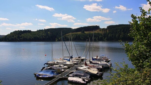 A calm lake with several boats docked at a pier. - Saaleland Apartment 3 (Schleiz)