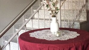 A round table with a red tablecloth and a white vase with flowers, placed on a staircase railing. - Saaleland Apartment 3 (Schleiz)