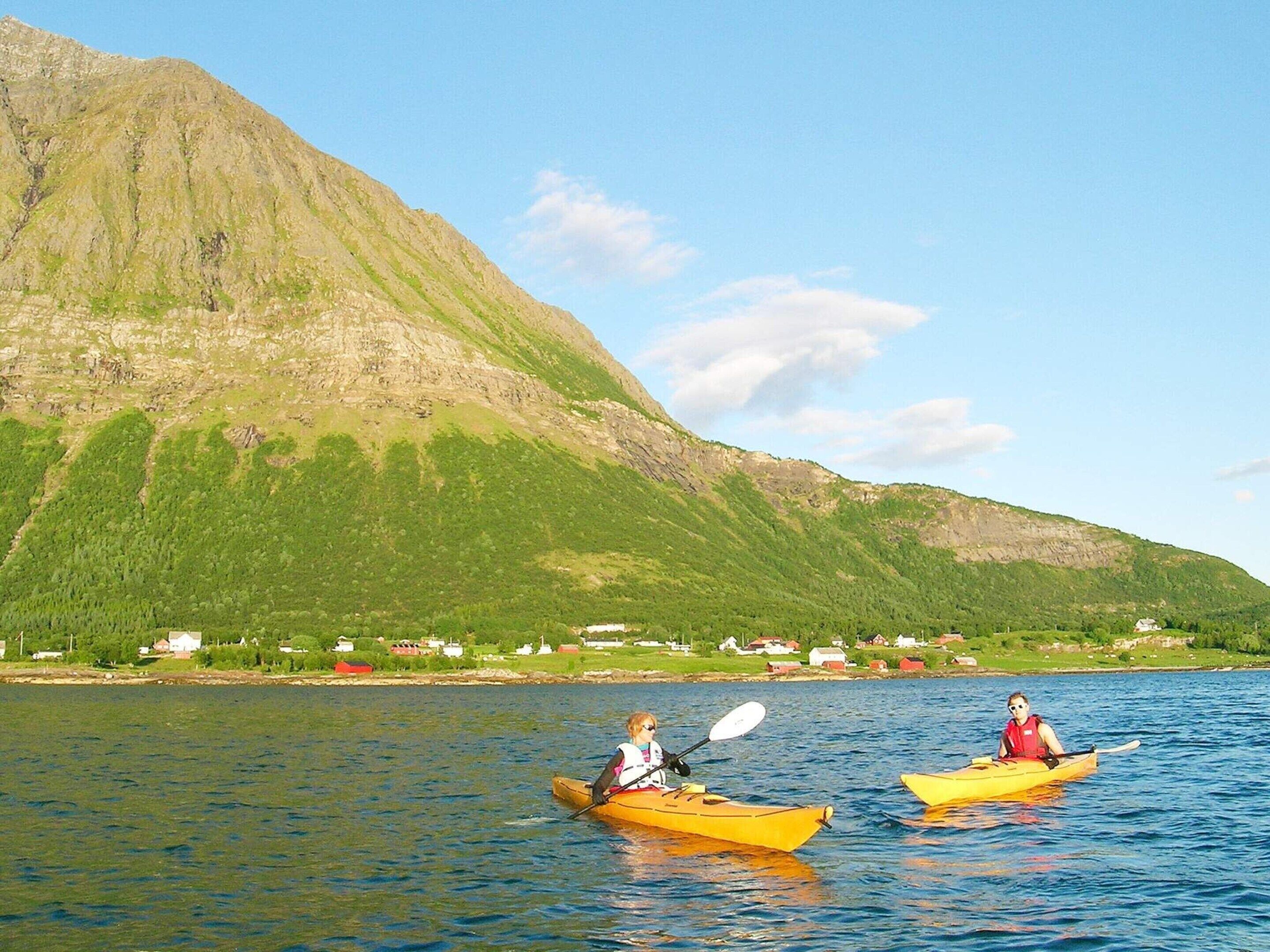Två kajaker på stilla vatten med ett berg i bakgrunden.