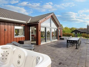 A modern house with a patio area featuring a hot tub, outdoor seating, and a dining table. - 5 Star Holiday Home in Haderslev (Haderslev)