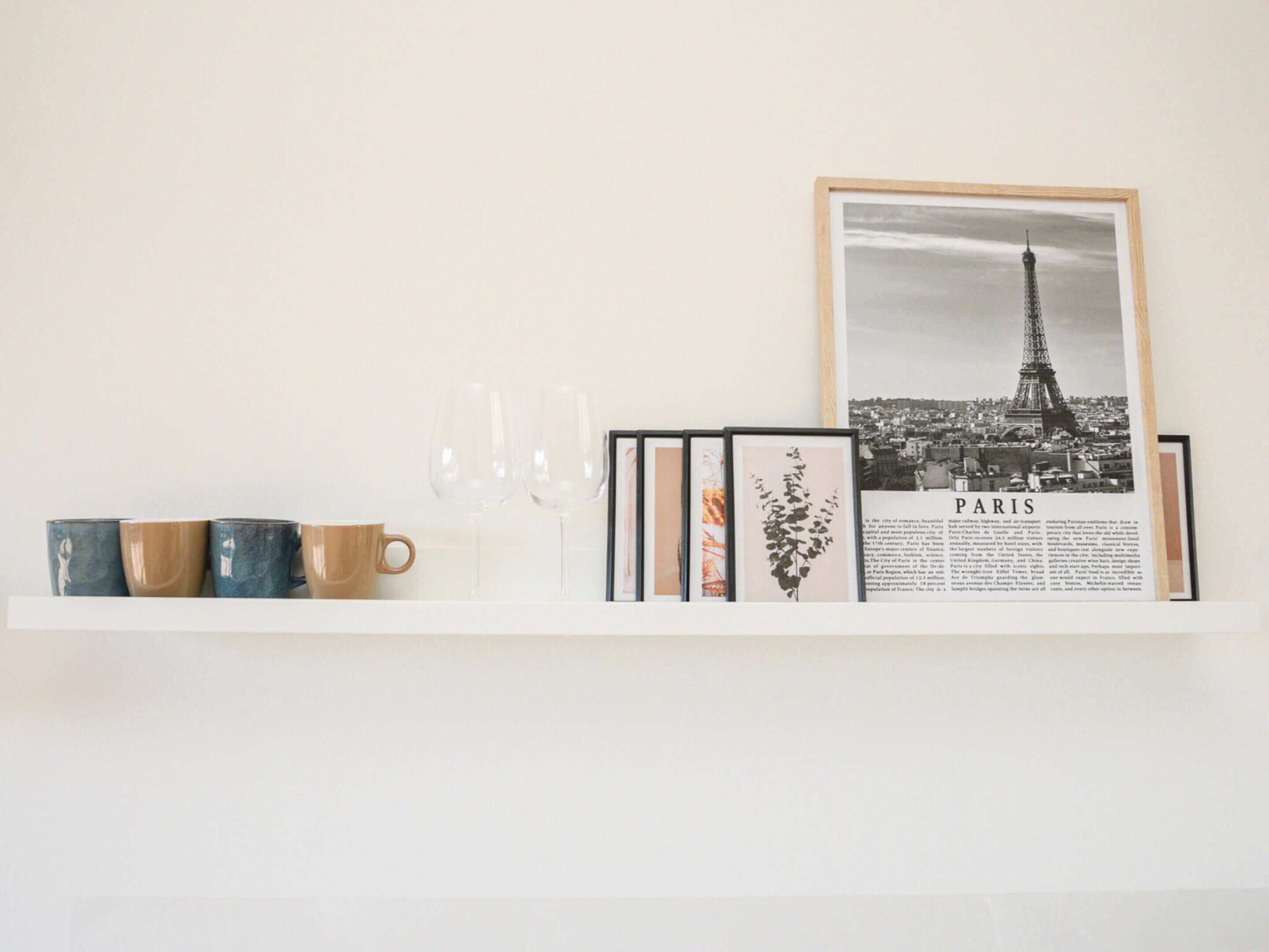 A wall with a framed Paris photograph, a small vase, and three cups.