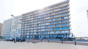 Un immeuble résidentiel à plusieurs étages, doté de balcons, d’un espace de stationnement et d’un lampadaire.