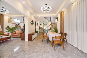 A spacious living area with a dining table, leather sofas, and a staircase leading to an upper floor. - KP VILLA - 6 ROOMS - 8 BEDS
Peaceful, full of natural light (Dalat)