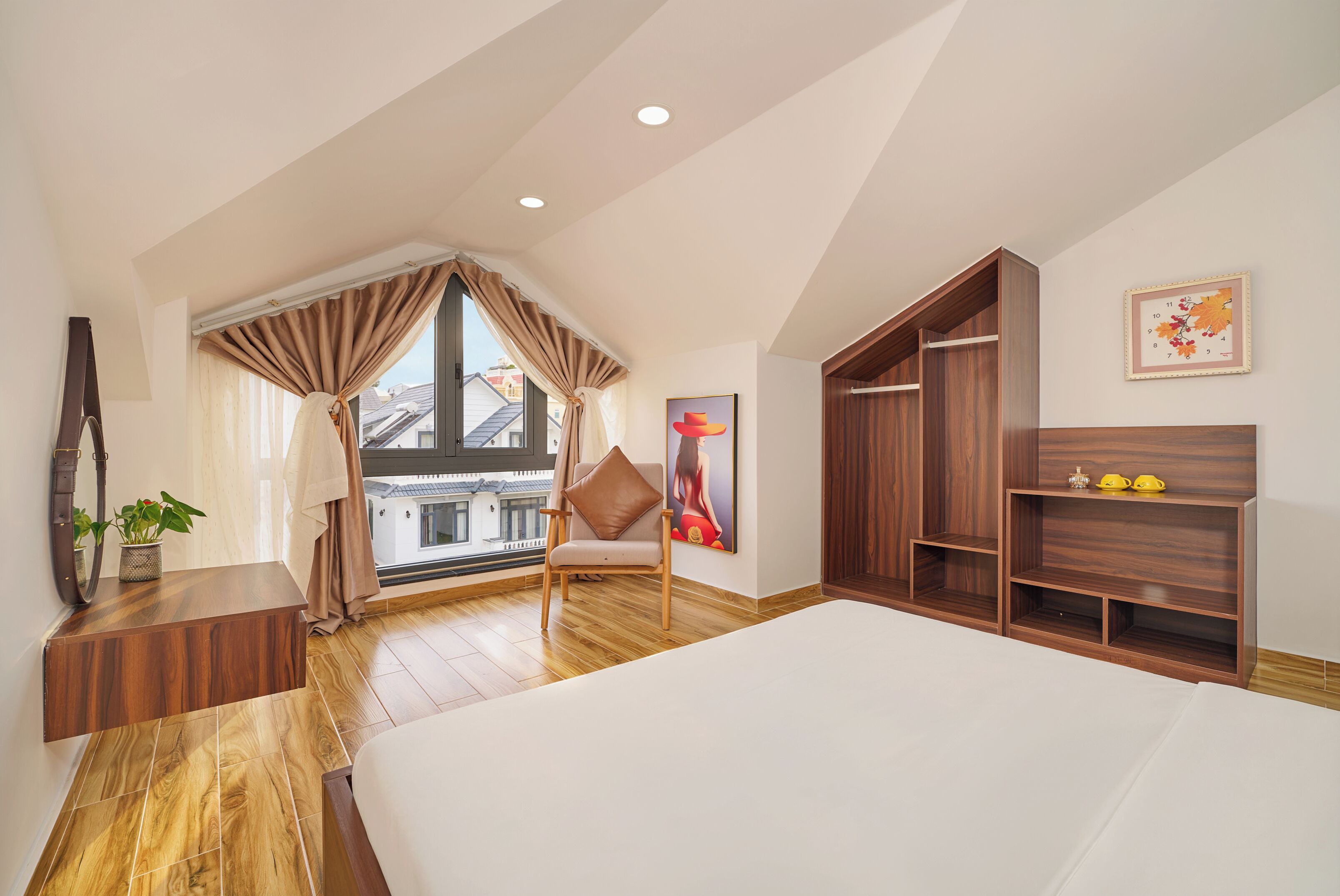 Ein Schlafzimmer mit einem großen Bett, Holzmöbeln, einem Sessel, einem Schreibtisch und einem Fenster mit Vorhängen.