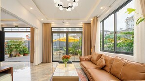 Un moderno vestíbulo de hotel con un sofá de cuero, una mesa de centro de vidrio y vistas al área exterior a través de amplias ventanas.