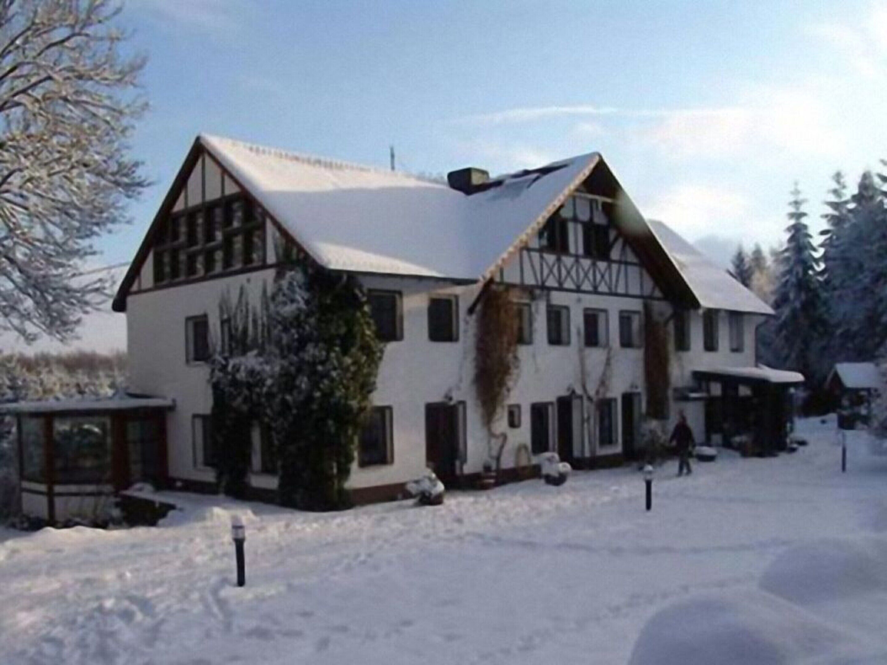 A large, two-story building with a steeply pitched roof, surrounded by snow.