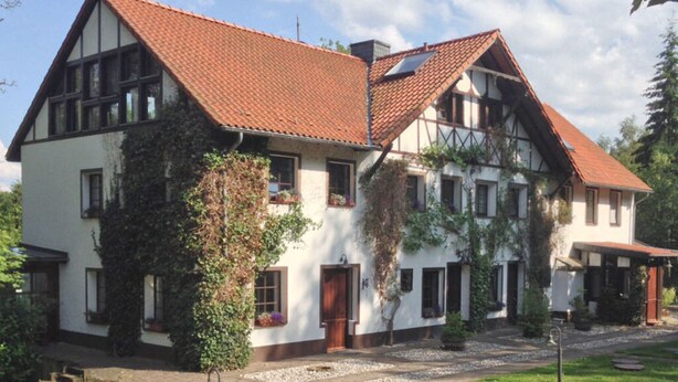 A traditional half-timbered house with a red-tiled roof, a garden with a pathway, and a small pond. - Holiday Apartment Waldquartier Wackerberg (Kall)