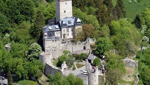 An aerial view of a castle with a prominent tower, surrounded by lush greenery and a moat. - Holiday Apartment Waldquartier Wackerberg (Kall)