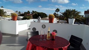 A rooftop terrace with a red table, two potted cacti, a decorative sculpture, and a bottle of champagne. - Villa Amelie Comfortable Holiday Residence (Pajara)