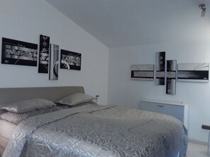 Une chambre moderne avec un grand lit, une table de chevet et un climatiseur fixé au mur.