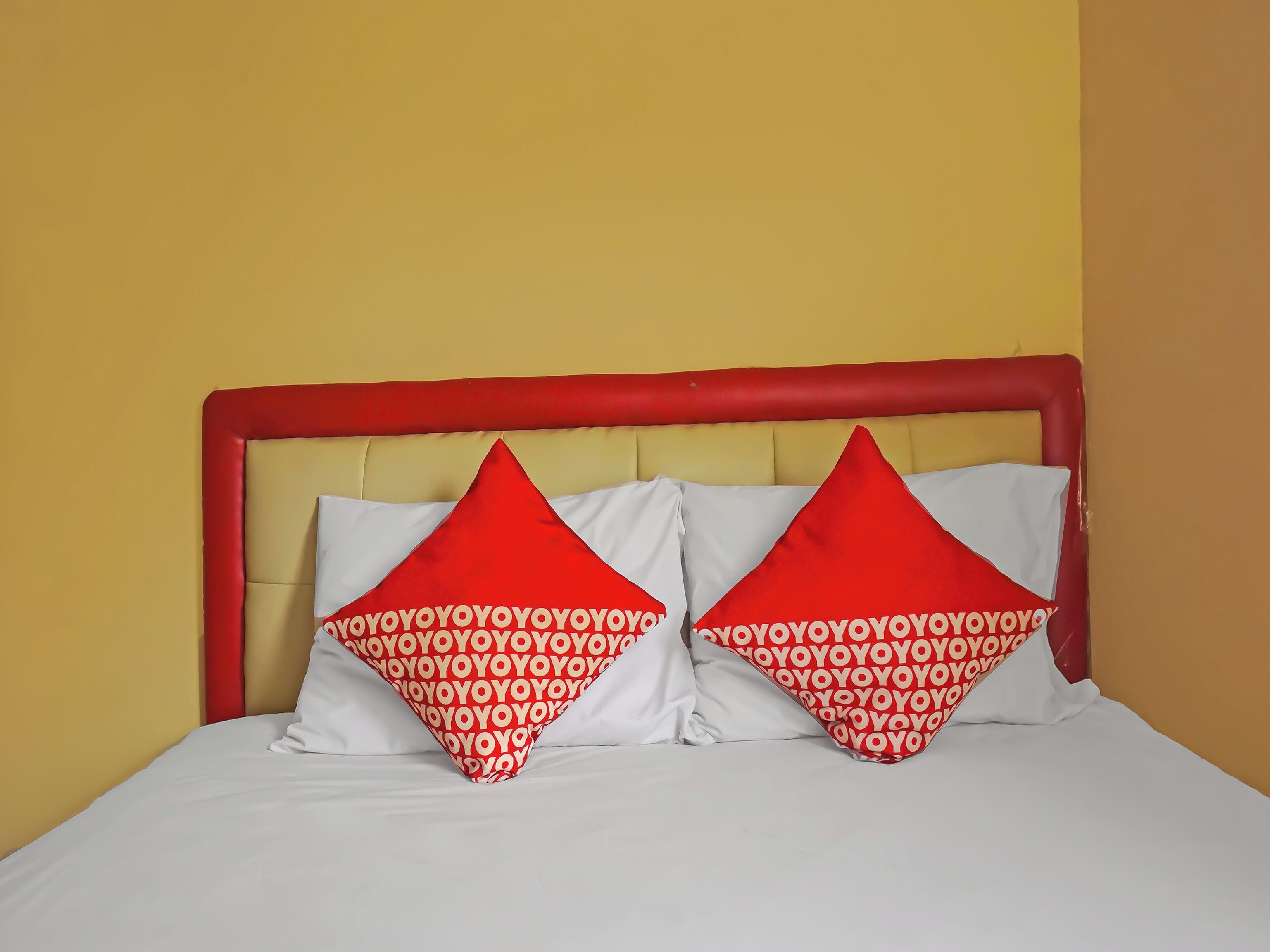 Cama com cabeceira vermelha e dois travesseiros com padrão vermelho e branco.