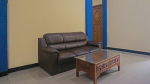 Een woonkamer met een bruine leren bank en een salontafel met een glazen blad.