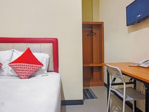 Une chambre d’hôtel équipée d’un lit, d’un bureau, d’une chaise, d’un téléphone et d’une télévision.