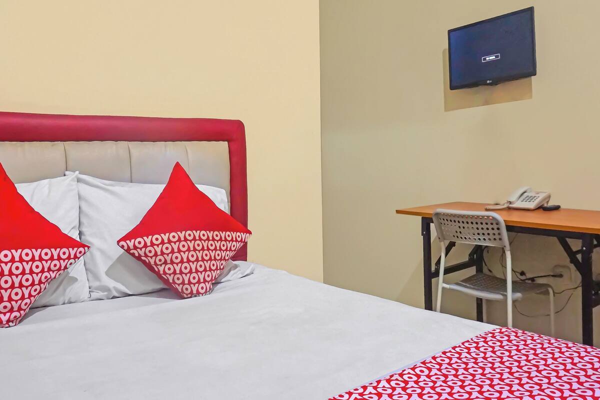 A hotel room with a bed, a desk, a chair, and a television.