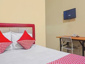 Une chambre d’hôtel équipée d’un lit, d’un bureau, d’une chaise et d’un téléviseur.