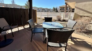 An outdoor patio with a table and chairs, a wooden fence, and a view of a residential area. - Lakefront Home away from Home (Osoyoos)