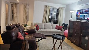 A living room with a sofa, a leather chair, a small table, and a cabinet.