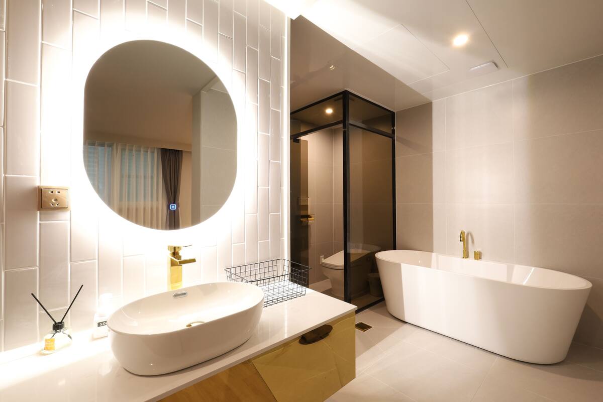 Une salle de bain moderne avec une baignoire sur pieds, un grand miroir ovale et un lavabo blanc.