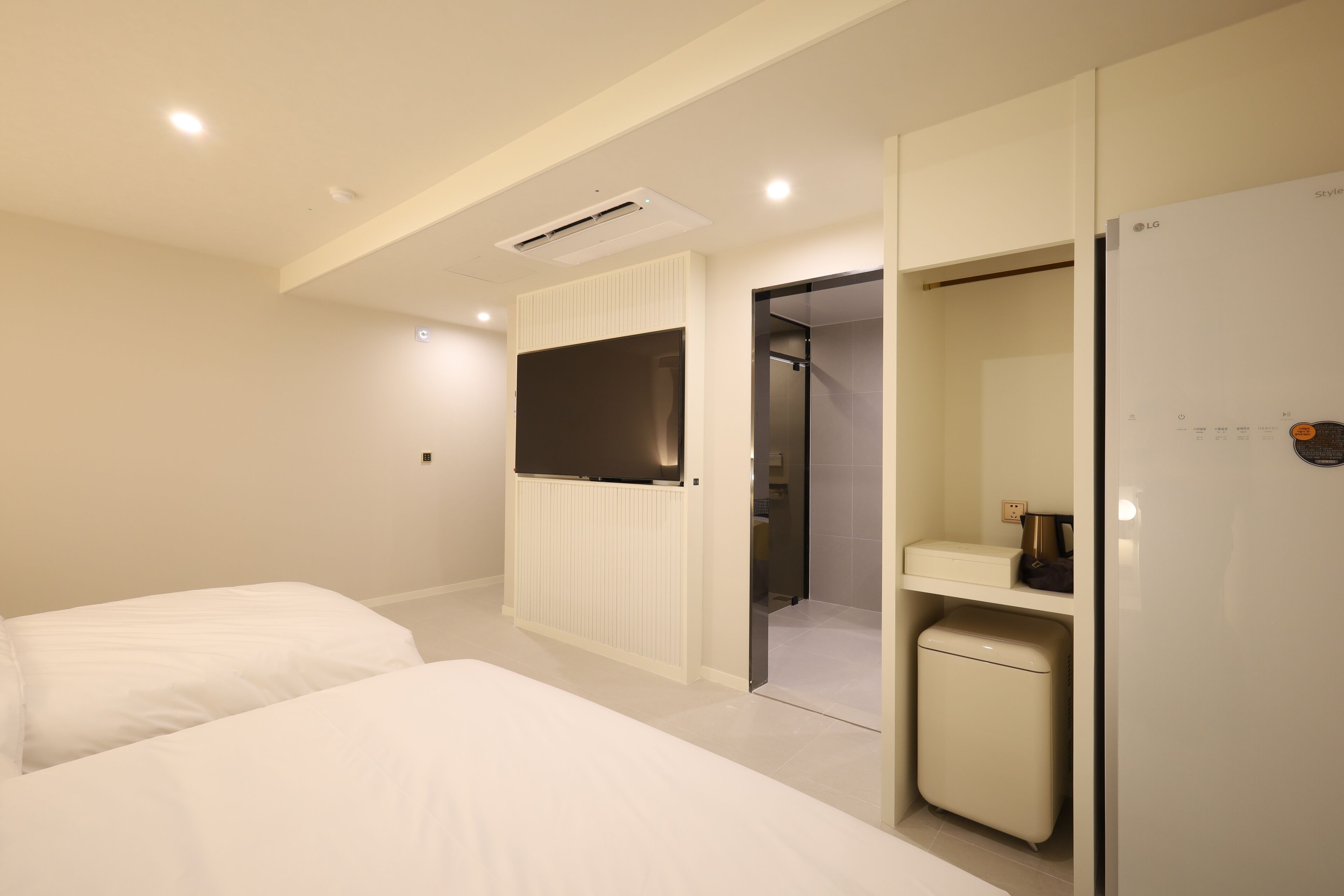 A modern hotel room with a bed, a wardrobe, a mirror, and a small cabinet.