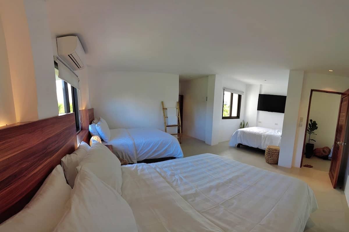 Habitación de hotel con dos camas, cabecero de madera, televisor de pantalla plana y ventana con vistas.