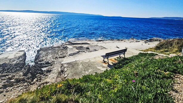 A rocky shoreline with a bench overlooking a bright blue sea. - Sun4Fun by Interhome (Trogir/Okrug Gornji)