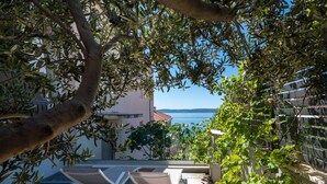 A terrace with lounge chairs, a view of the sea, and a building with a red roof in the background. - Sun4Fun by Interhome (Trogir/Okrug Gornji)