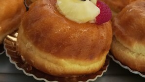 Exhibición de pasteles con frutas en un ambiente de panadería.