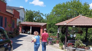 Una calle residencial con casas, un coche aparcado y un pabellón con plantas en macetas.