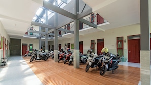 A multi-level indoor parking area with several motorcycles parked under a skylight. - SPOT ON 93965 Ibrahim Guest House Syariah (Ngasem)