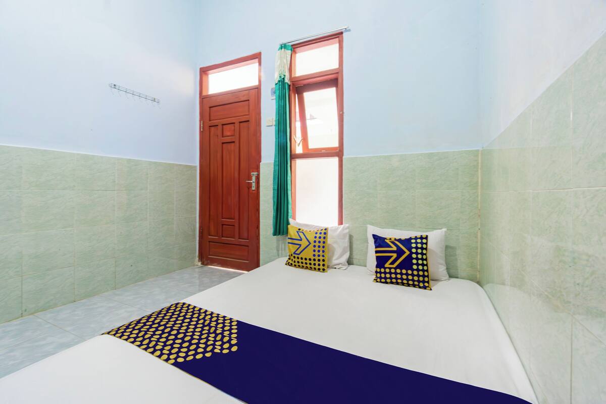 Ein Hotelzimmer mit Bett, zwei Kissen, einem Fenster und einer Tür.