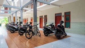 A multi-level indoor area with a row of parked motorcycles and bicycles. - SPOT ON 93965 Ibrahim Guest House Syariah (Ngasem)