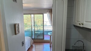 Een kleine keuken met een spoelbak, kastjes en uitzicht naar buiten.