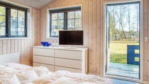 Un dormitorio con cama, cómoda, televisor y ventana grande.