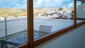 A balcony with a view of a town, a patterned mat, and a chair. - Holiday Home in Andalucia Near Caminito del Rey (Arcos de la Frontera)