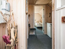 Un pasillo estrecho con una cama al fondo, un escritorio y una silla.