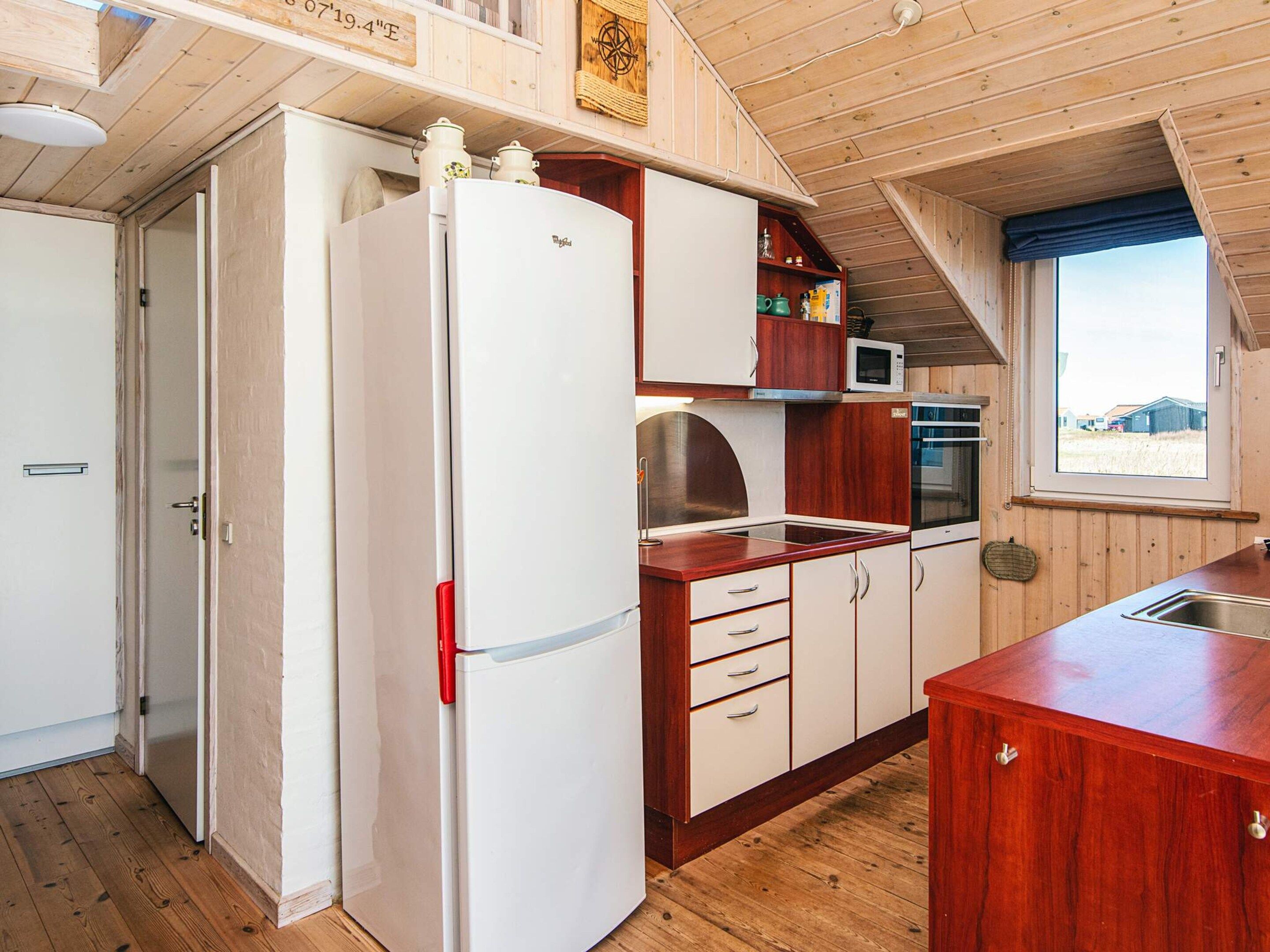 A compact kitchen with a refrigerator, microwave, stove, and wooden cabinets.