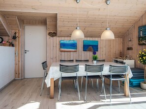 A wooden interior with a dining table, chairs, pendant lights, and artwork on the walls. - 8 Person Holiday Home in Lemvig (Lemvig)