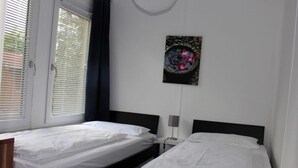 A hotel room with two single beds, a bedside table with a lamp, and a wall-mounted artwork. - Bungalow Oberspreewald 3 (Schwielochsee)