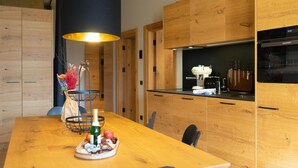 Una cocina moderna con armarios de madera, encimera negra y lámpara colgante.