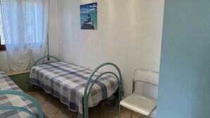 A small, clean room with two beds, a chair, and a picture on the wall. - Solaris by Interhome (Rosolina Mare)