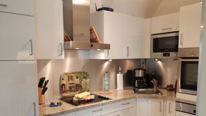 Eine moderne Küche mit weißen Schränken, Edelstahlgeräten und einem eingebauten Backofen.