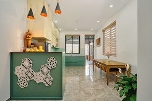 A modern kitchen with a green accent wall, a dining area with a wooden table, and pendant lighting.