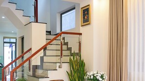 Un interior moderno con una escalera, zona de comedor y una araña.