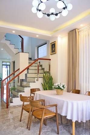 Un interno moderno con una scalinata, zona pranzo e un lampadario.