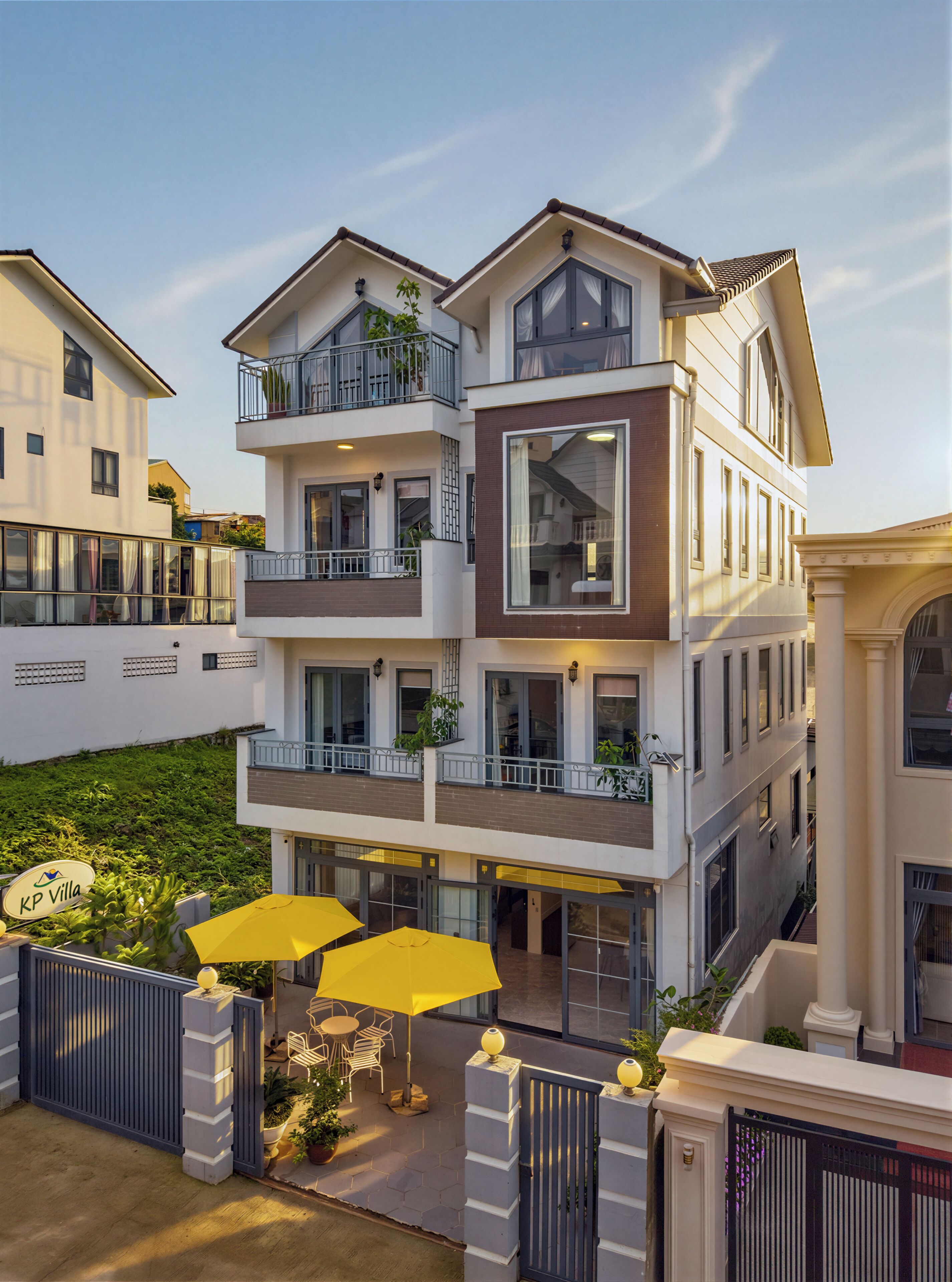 A multi-story hotel with balconies, outdoor seating, and a gated entrance.